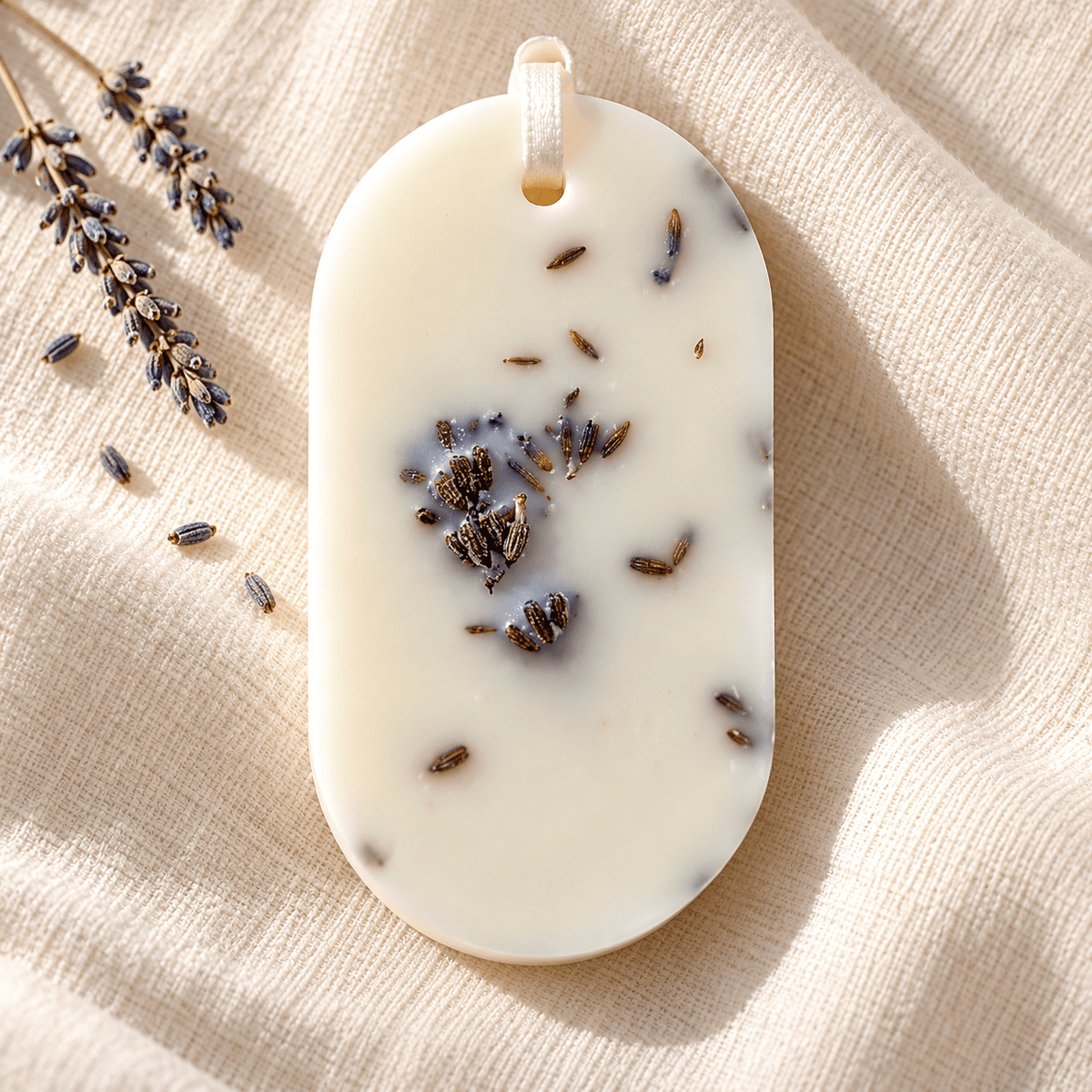 Odorizant pentru dulap din ceară naturală, decorat cu flori uscate de lavandă, cu parfum de lavandă și așezat pe o pânză textilă ivory.